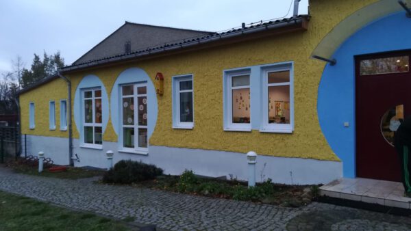 Gelb-blaues Gebäude mit Fenstern und roter Eingangstür